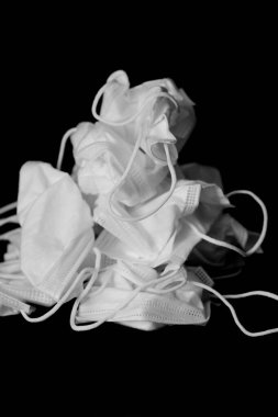 Siyah arka planda beyaz tıbbi maske kullanılmış. Fotokopi alanı ile tıbbi atık ve kirlilik kavramı