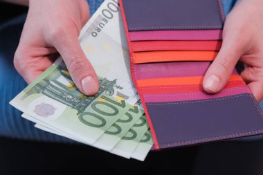 Cüzdanı banknotlu bir kadın el ele tutuşuyor, yakın plan. Para ve finans kavramı