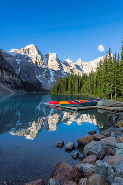 Beautiful sunrise at the Moraine Lake with snow-covered peaks above it in Rocky Mountains, Banff National Park, Canada.
