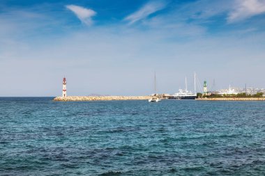 Türkiye 'nin Bodrum kentinde güneşli bir günde limanda deniz feneri ve yelkenli tekneleri.