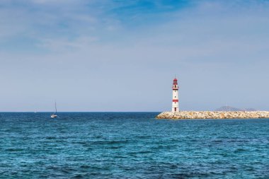 Türkiye 'nin Bodrum kentinde güneşli bir günde limanda deniz feneri ve yelkenli tekneleri.