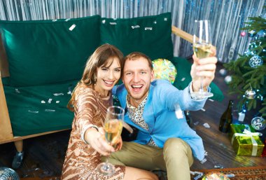 Şampanyalı neşeli çift kameraya bakıyor, Noel 'i ya da yeni yılı kutluyor.