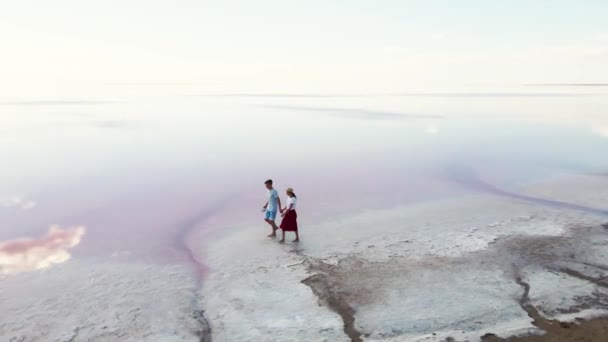 Romantik çift pembe gölün tuzlu kıyısında sarılıp öpüşüyor. — Stok video