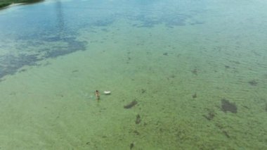 Yavaş çekim drone görüntüsü. Sarı bikinili kadın denize giriyor.