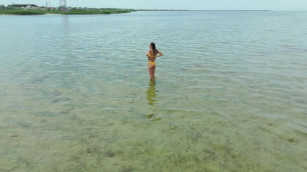 Slow motion drone beeldmateriaal vrouw in gele bikini gaan in de zee — Stockvideo