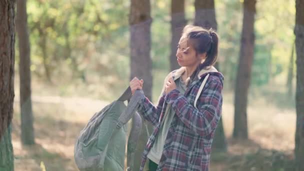 Donna hipster viaggiatore mette su piccolo zaino nella foresta autunnale — Video Stock