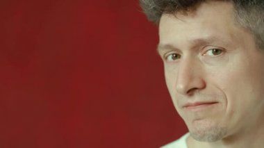 Kırmızı duvardaki mutsuz ve hayal kırıklığına uğramış genç adam.