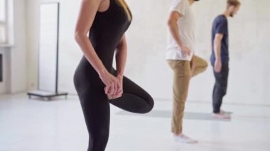 Bir grup genç sporcu yoga yapıyor, spor yapıyor, kapalı bir yerde, stüdyoda. Önplandaki çekici sarışın kadın..