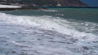 Çakıl taşlı deniz sahilinde ağır çekim dalgaları.