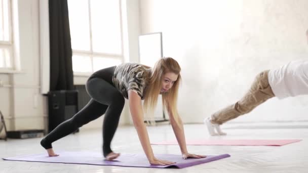 Atractiva mujer flexible que hace ejercicio en el estudio de yoga, haciendo estiramiento de nuevo en la estera. — Vídeo de stock