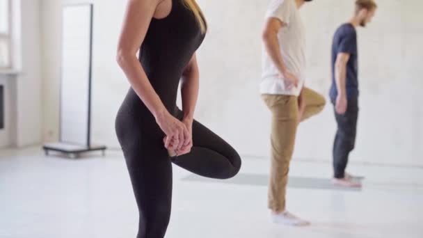 Skupina mladých sportovců cvičí jógu, cvičí, v interiéru, ve studiu. atraktivní blondýna žena v popředí. — Stock video