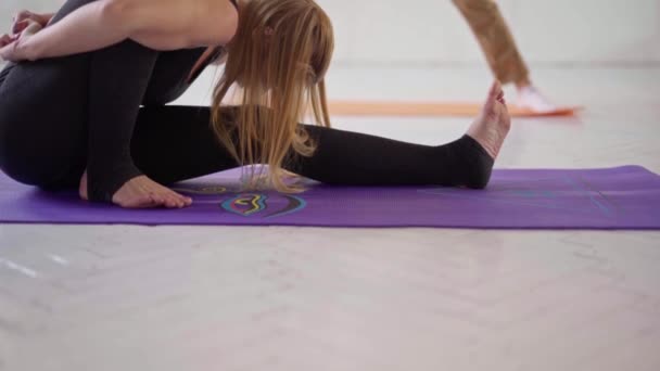 Par i vit yogastudio. sportig flexibel kvinna i svarta sportkläder som utövar yoga i yogaklassen — Stockvideo