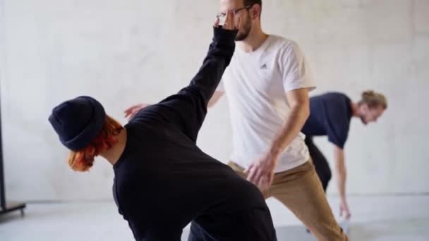 Junge außergewöhnliche weibliche Yogalehrerin hilft Mann Student Stretching Indoor. — Stockvideo
