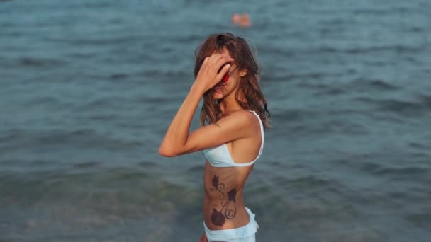 Lassú mozgás gyönyörű bájos fiatal nő fehér bikini a tengeren háttér — Stock videók