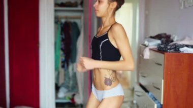 Ağır çekimde gülümseyen kadın üstte ve iç çamaşırı evde egzersiz yapıyor.