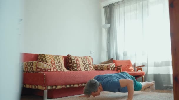 Spor kıyafetli güçlü kaslı adam evde egzersiz yapıyor. — Stok video