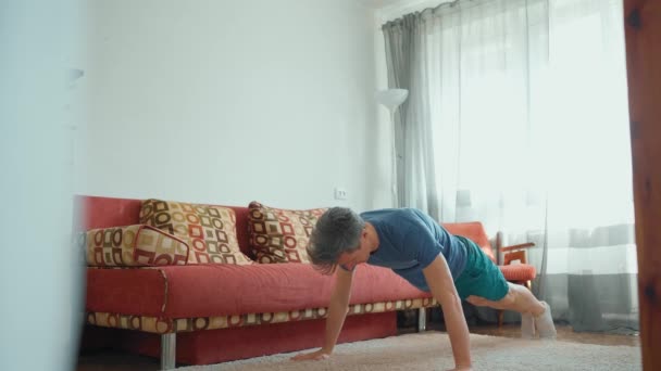 Strong muscular man in sportswear doing exercises at home — Stock Video