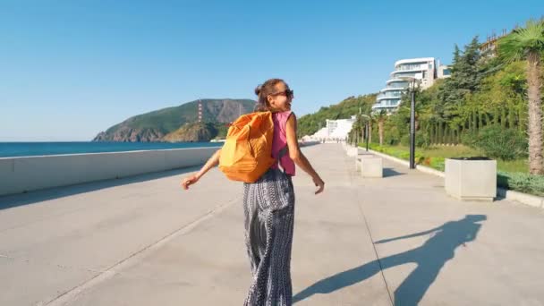 夏の朝バックパック付きの女の子旅行者が海辺を走っています — ストック動画