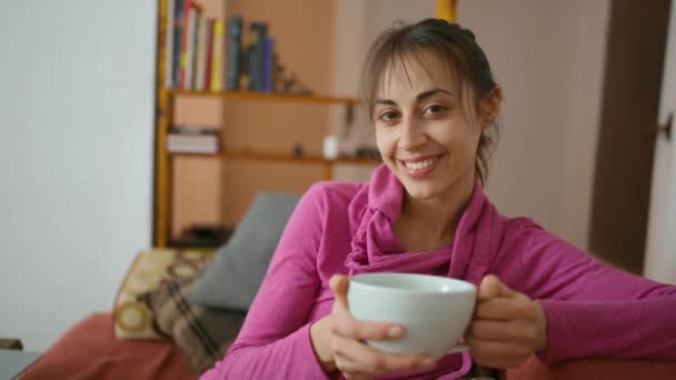 Mulher em suéter rosa no sofá com grande xícara de chá — Vídeo de Stock