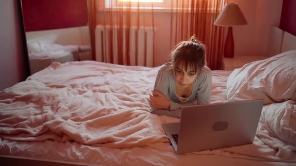 Γυναίκα ελεύθερος επαγγελματίας ή φοιτητής ξαπλωμένος κρεβάτι χρησιμοποιώντας φορητό υπολογιστή κατά τη διάρκεια καραντίνας — Αρχείο Βίντεο