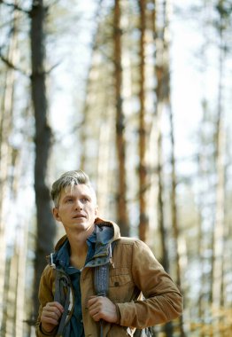 Portre hazırlayan adam ormanda duruyor. İyimser bir bakış açısı, güneşli bir hava.