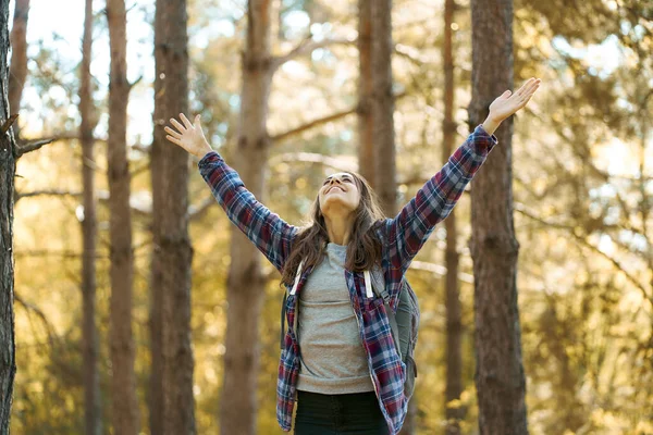 Entzückte positive Frau mit erhobenen Händen genießt schöne Natur im Wald. — Stockfoto