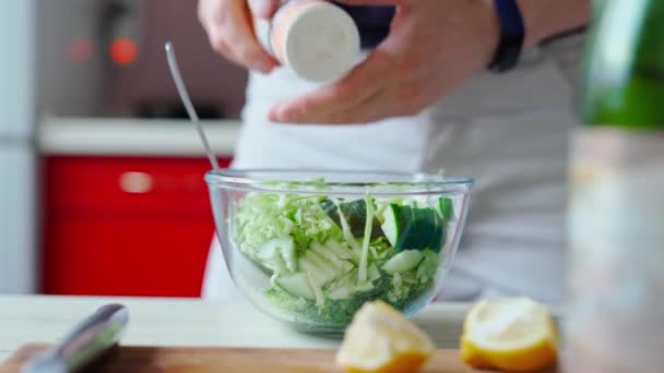 Detailní záběr mužské ruce dává sůl na zelený zeleninový salát — Stock video