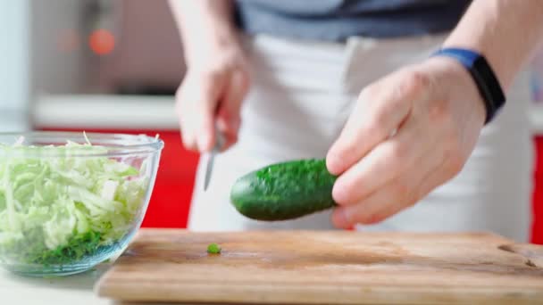 Мужские руки с ножом режет свежий огурец для зеленого салата — стоковое видео