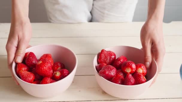 Honans händer tar rosa skålar med jordgubbar och visar till kameran — Stockvideo