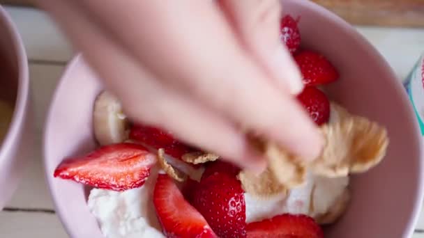 Närbild sätta flingor i skålen med skuren jordgubbe — Stockvideo