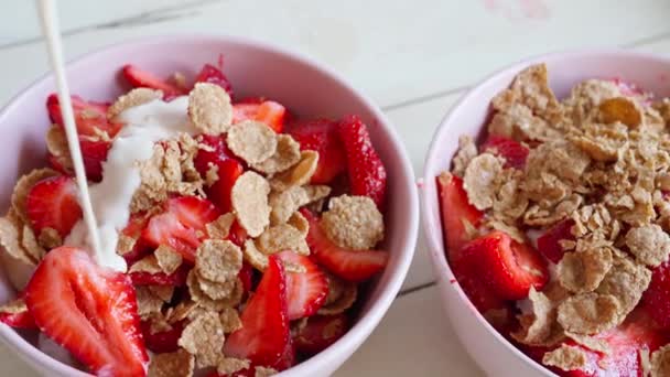 Verter yogur en un tazón lleno de fresas cortadas y copos — Vídeo de stock