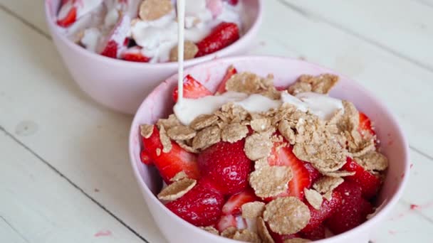 Yoghurt in een kom met gesneden aardbeien en vlokken gieten — Stockvideo