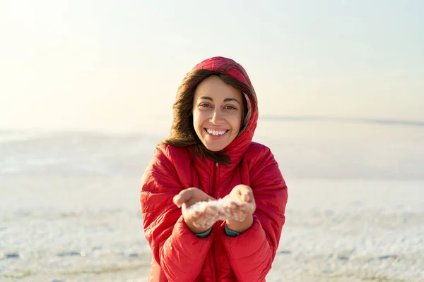 Outdoor sole luce ritratto felice ragazza in giacca rossa sorridente alla macchina fotografica e tenendo cristalli di sale in mano a bellissimo paesaggio di Salt Flats — Foto Stock