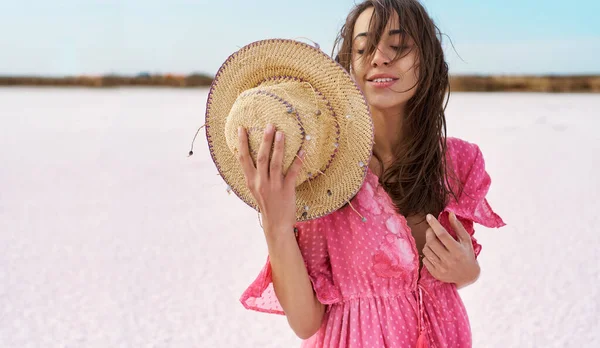 Романтическая женщина в розовом платье и шляпе на солончаках на розовом озере — стоковое фото