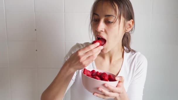 Wanita memegang mangkuk dengan stroberi dan makan berry — Stok Video