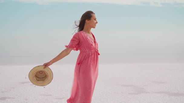 Mujer de la libertad en vestido rosa y sombrero despreocupado y feliz con los brazos abiertos en el cielo azul blanco paisaje de playa de sal. Sentir felicidad — Vídeos de Stock