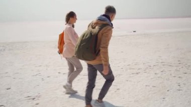 Mutlu, sevimli birkaç bin yıllık hippi el ele yürüyor ve pembe, beyaz, tuzlu sahilde neşeyle koşuyor.