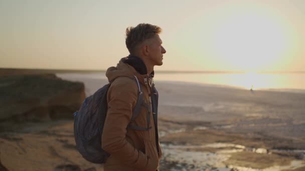 無人の海のビーチで日の出に会うバックパック付きの旅行者 — ストック動画