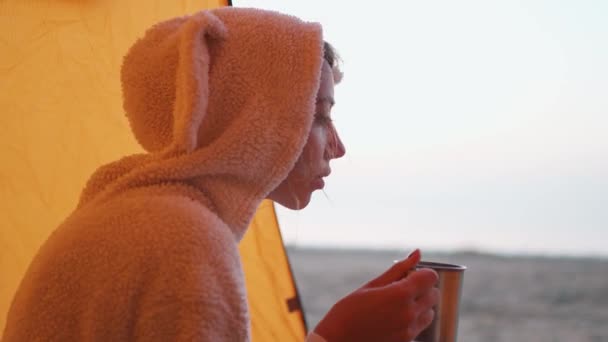 Woman Traveler in funny bunny pajama Enjoying Hot Tea In Mug On beach in tent at cold morning. — Stock Video