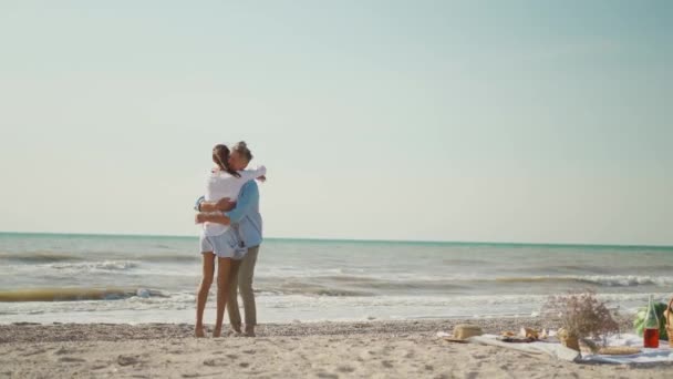 Красивий лютуючий радісний чоловік і жінка, що виступає на пляжі на узбережжі і чоловік кладе свою дівчину на руки і спину — стокове відео