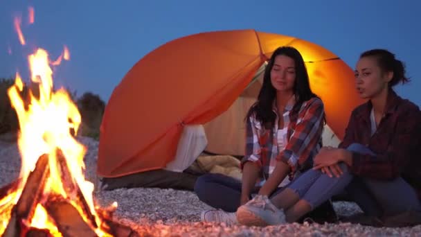 2人の美しい女の子座ってたき火の近くにオープンオレンジテント — ストック動画