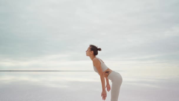 Junge schlanke Mischlingsfrau praktiziert Yoga am Strand bei Sonnenaufgang — Stockvideo