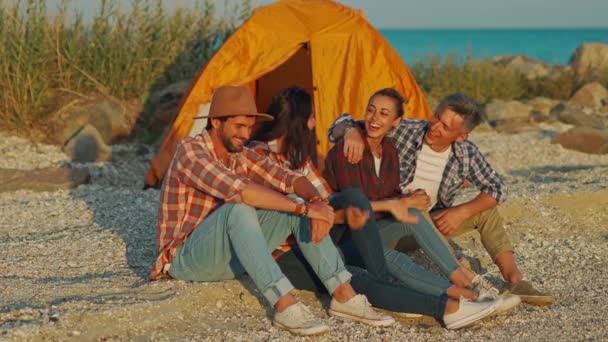 Cuatro amigos sentados al amanecer en la playa frente al mar — Vídeo de stock