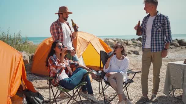 Czterech dorosłych przyjaciół podróżników korzystających z zimnego piwa w gorący słoneczny dzień na kempingu na morskich Coas — Wideo stockowe