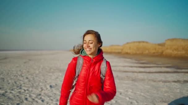 Slow motion fri glad ung vandrare kvinna i röd jacka skrattar och kör på salt öken, torr kust mineralsalt sjö — Stockvideo