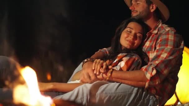 Muž objímání žena v přední části ohně na pláži párty ve tmě. — Stock video