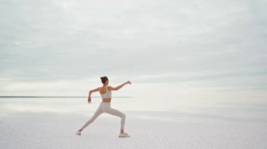 Sabit kamera, Yoga yapan kadın plajda çalışıyor ve güneş doğarken plajda dinleniyor.
