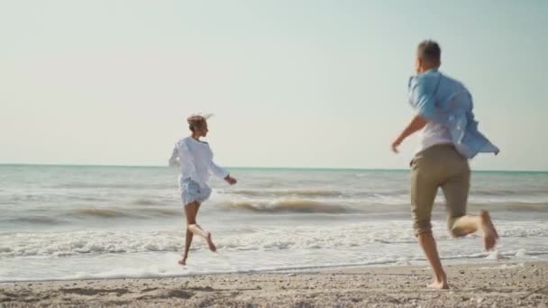 Gioiosa bella coppia avendo divertimento corsa lungo sabbia spiaggia insieme — Video Stock