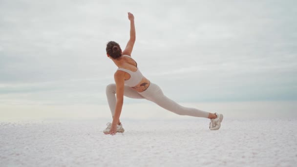 Струнка брюнетка робить йогу на свіжому повітрі. Жінка практикує йогу в пустелі солоного озера. Жінка робить йогу на відкритому повітрі . — стокове відео