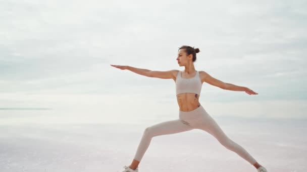 Giovane donna atletica che esegue posa yoga sulla costa deserta infinita lago salato all'alba — Video Stock